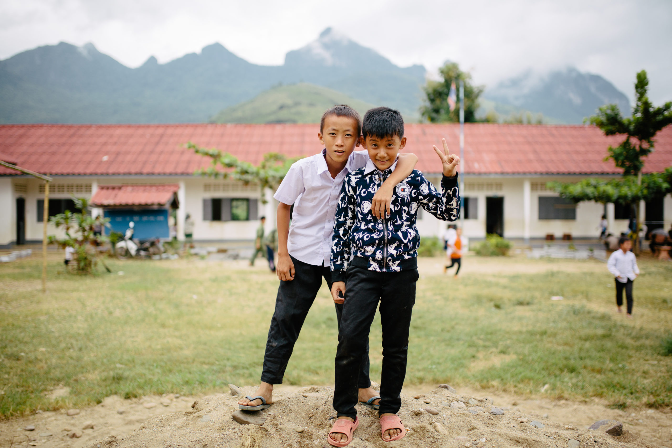 Two students in Laos stand outside of a PoP-built school.